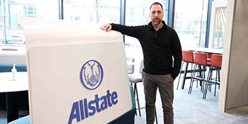 Steven McKeown standing next to an Allstate sign. 