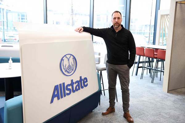 Stephen McKeown standing next to a sign that says Allstate. 