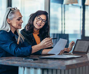 Two co-workers discussing work at a table. 