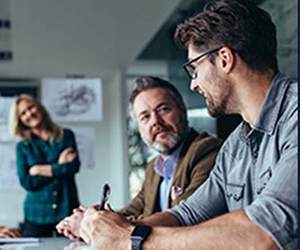 A person explaining work to the another while sitting at a desk. 
